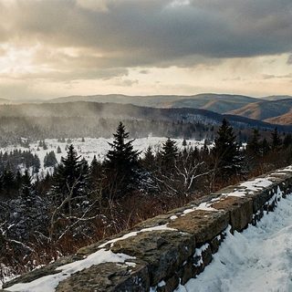 Rime covered red spruce along a snow packed mountain road under low gray cloud